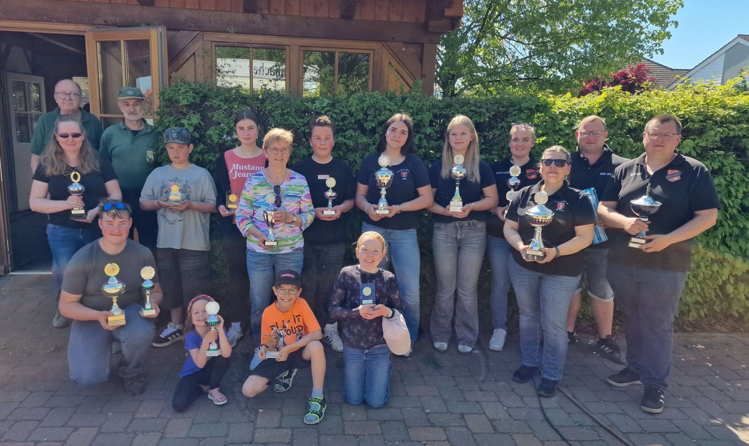 Das Bild ist ein Gruppenfoto, wo viele Personen (Kinder und Erwachsene) mit Pokalen zu sehen sind.